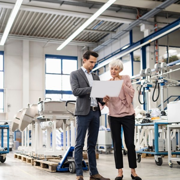 Businessman and senior woman looking at plan in a factory