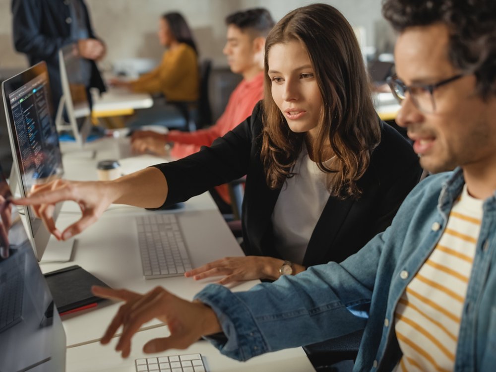 Diverse Multiethnic Group of Female and Male Students Sitting in College Room, Collaborating on School Projects on a Computer. Young Scholars Study, Talk, Apply Academic Skills and Knowledge in Class.