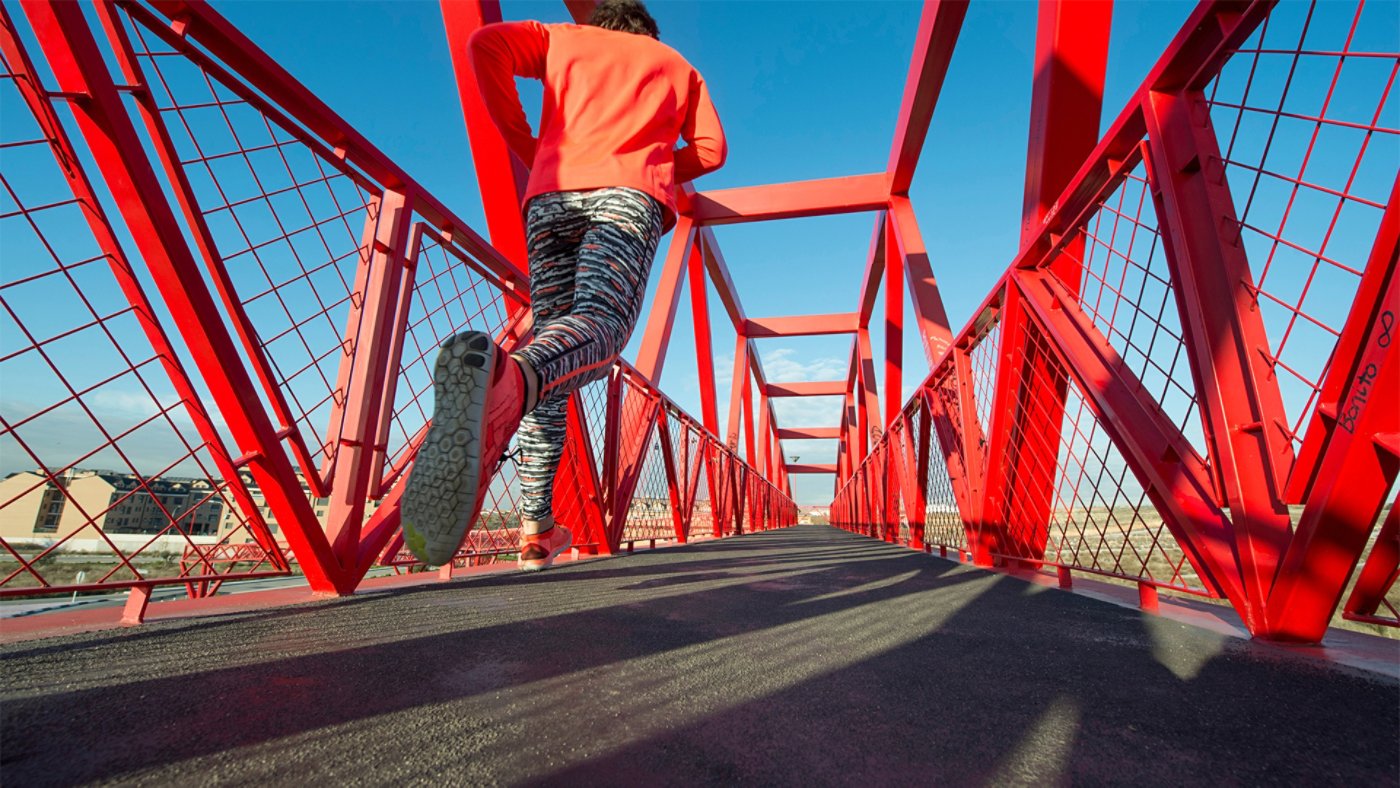 jogger crossing red pedestrian bridge