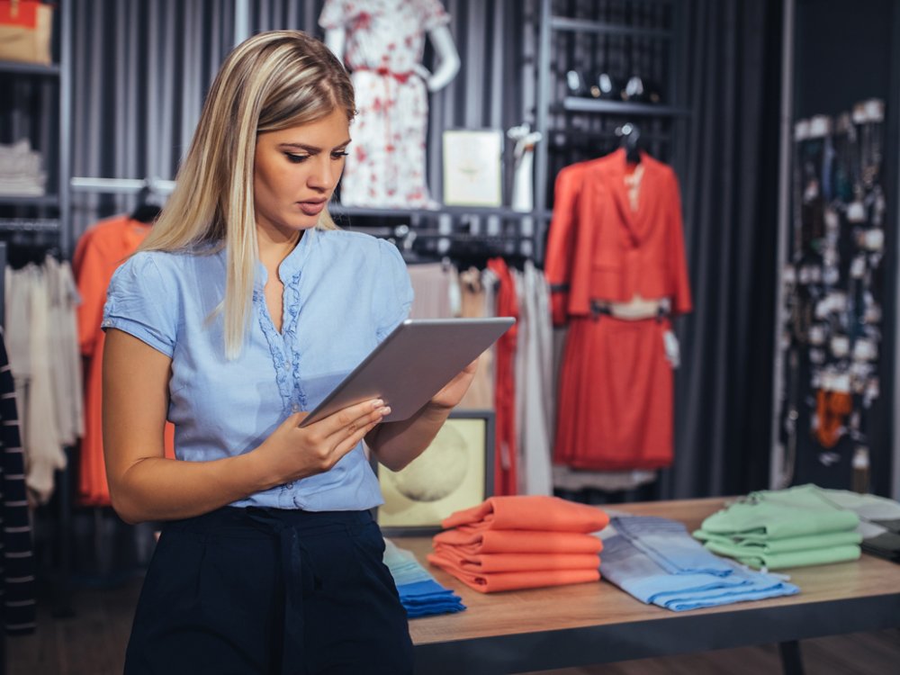 Photo of a young woman using digital tablet in the store.