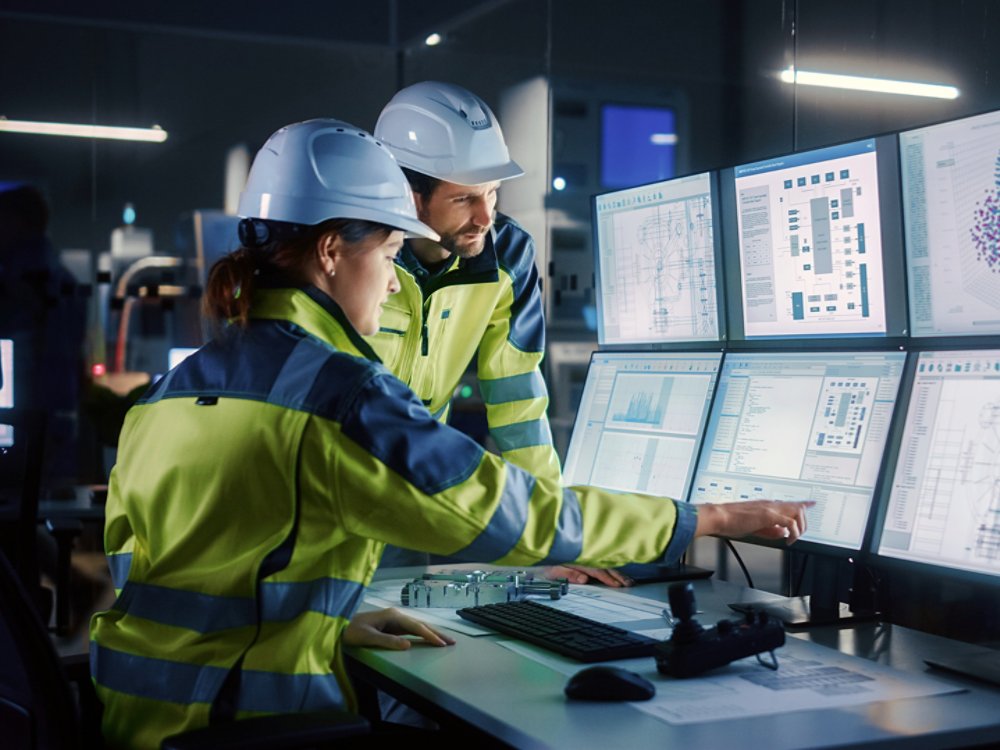 Industry 4.0 Modern Factory: Project Engineer Talks to Female Operator who Controls Facility Production Line, Uses Computer with Screens Showing AI, Machine Learning Enhanced Assembly Process