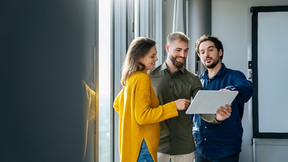 Smiling businessman discussing with colleagues over tablet PC in office
