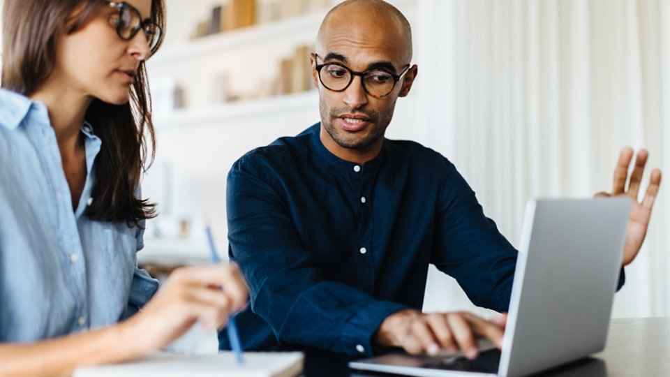 IT consulting expert using a laptop and discussing with his customer in an office.