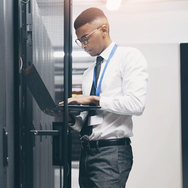 Man, technician and server room with laptop for software, hardware or network repair at office. Male person, IT engineer or fix with computer for technical solution, internet service or system backup.