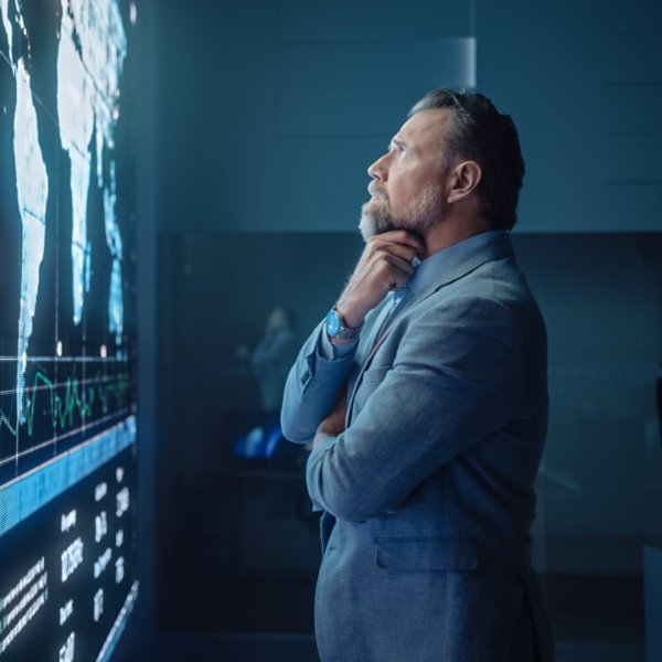 Senior Computer Science Engineer Looking at Big Screen Display Showing Global Map with Data Points. Telecommunications Technology Company System Control and Monitoring Room with Servers.