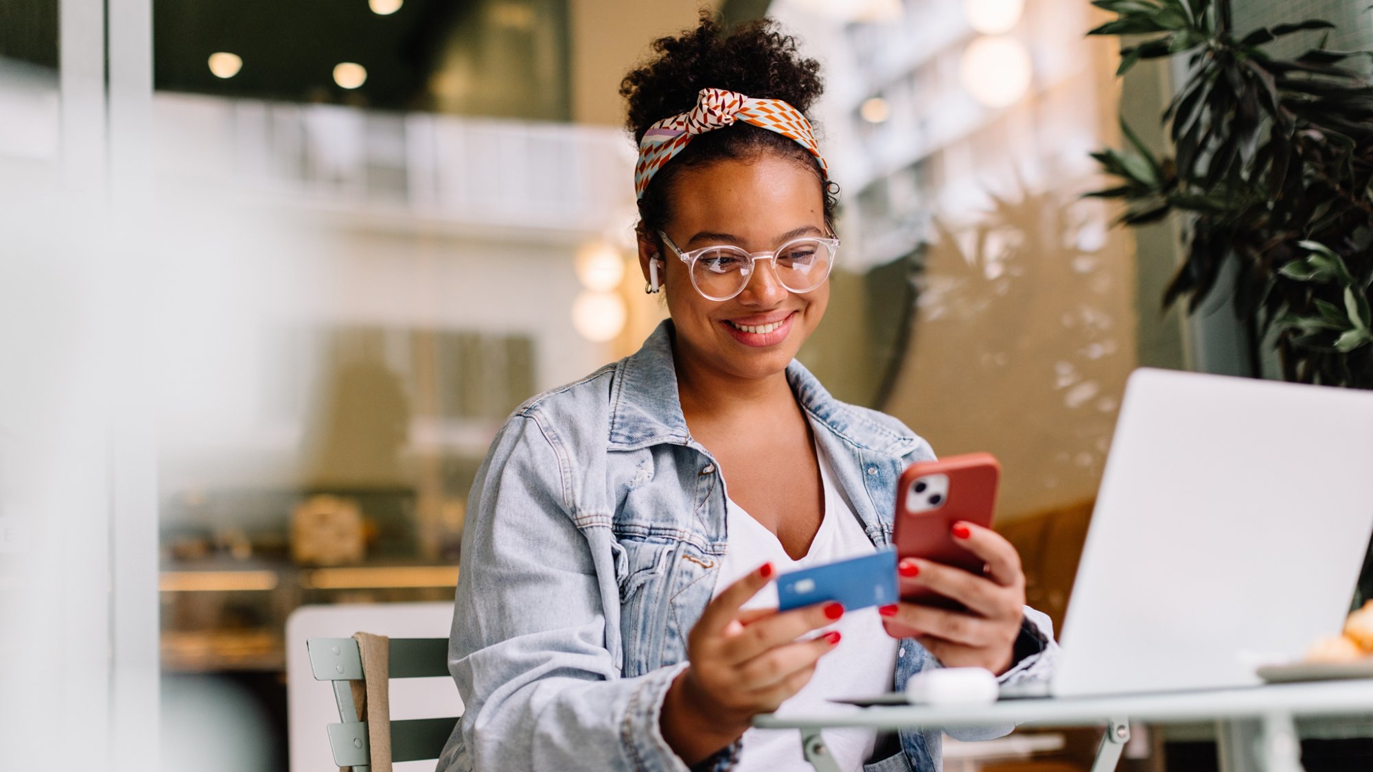 Happy entrepreneur uses a cellphone for online shopping and payment in a cozy café. Technology and business seamlessly combine in this real lifestyle moment.