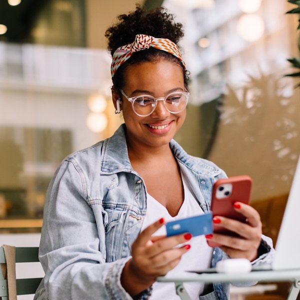 Happy entrepreneur uses a cellphone for online shopping and payment in a cozy café. Technology and business seamlessly combine in this real lifestyle moment.