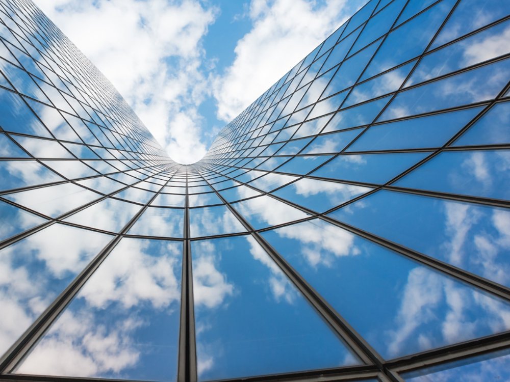 Blue sky and white clouds reflecting in a curved glass building