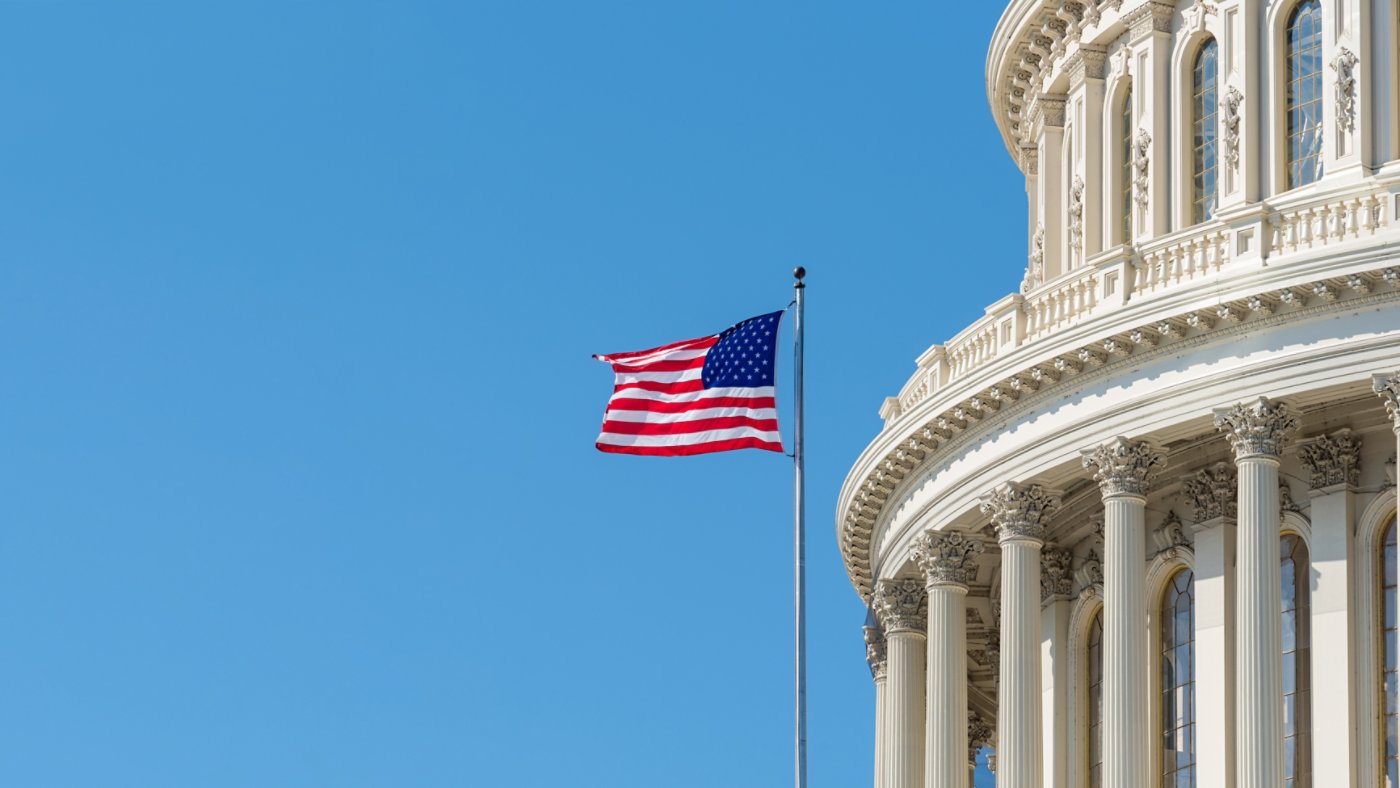 Cupola or dome of the US Capitol building in Washington DC with an American stars and stripes flag flying on a flagpole