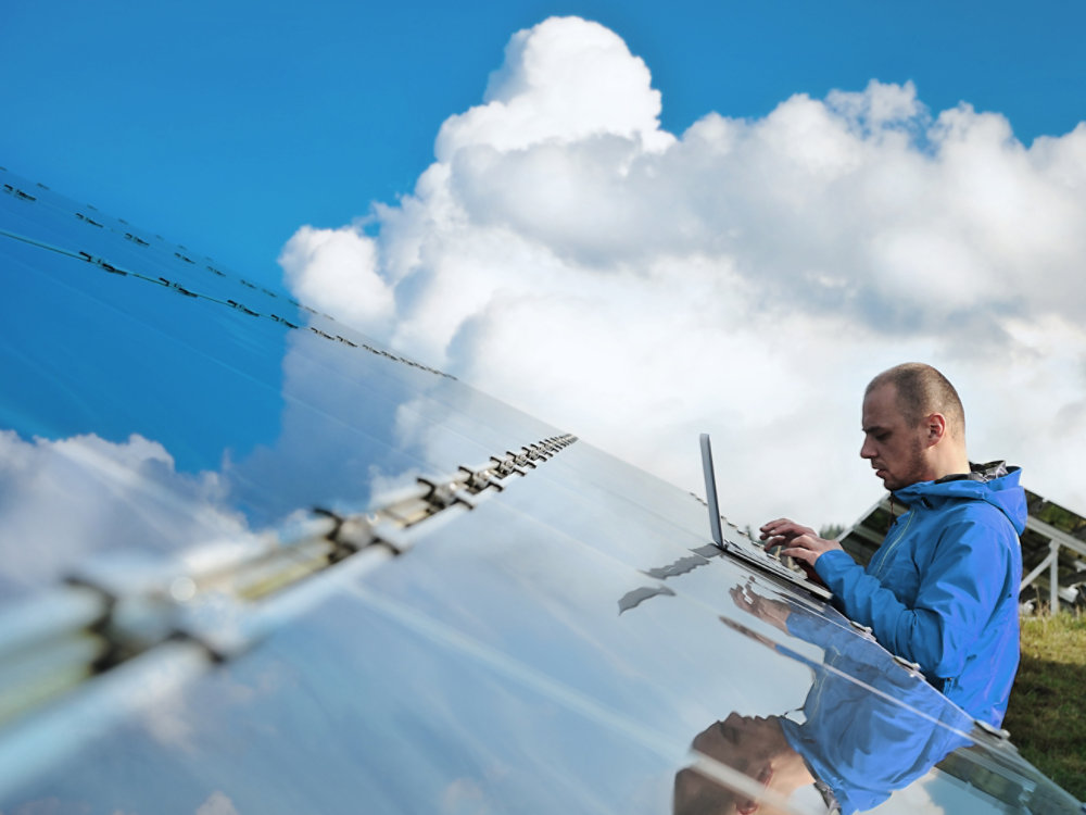 Male engineer with laptop working on solar panels