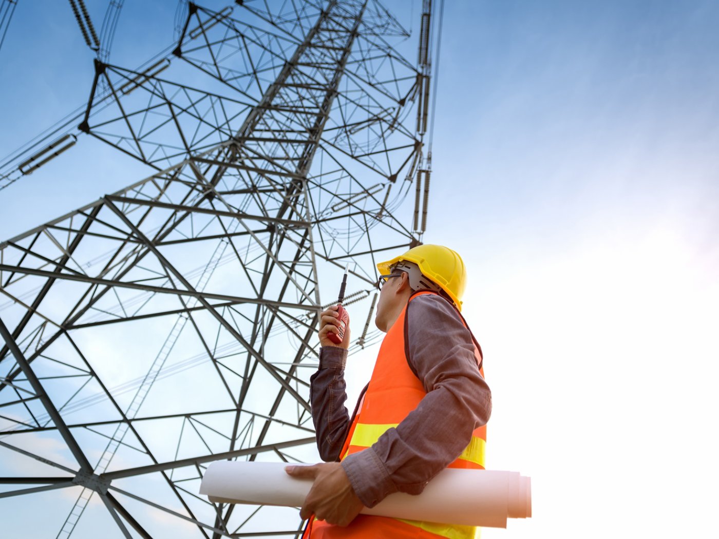 Construction worker checking location site near to High voltage tower.