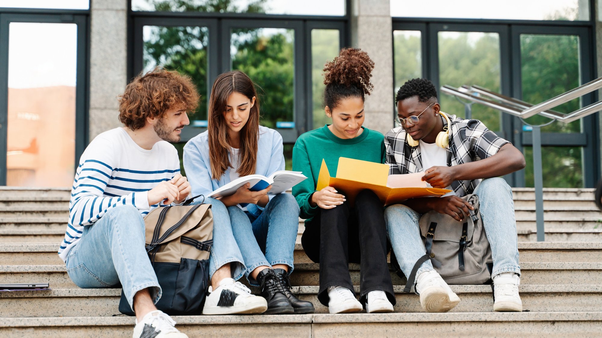 Young students sitting on University stairs. College friends studying together after class 