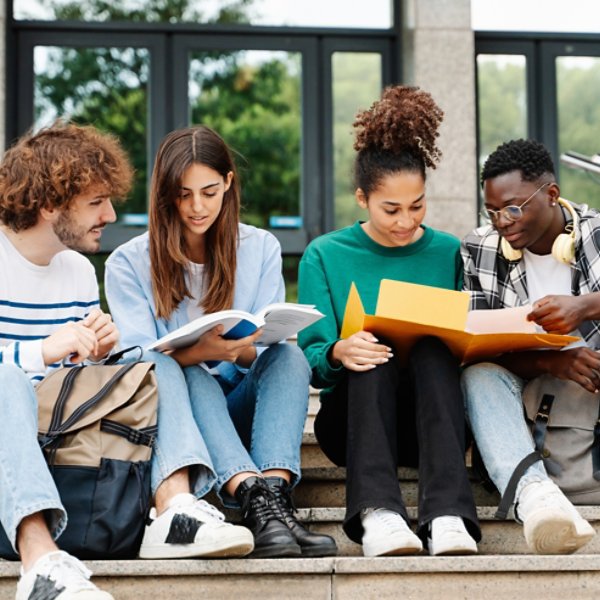 Young students sitting on University stairs. College friends studying together after class 