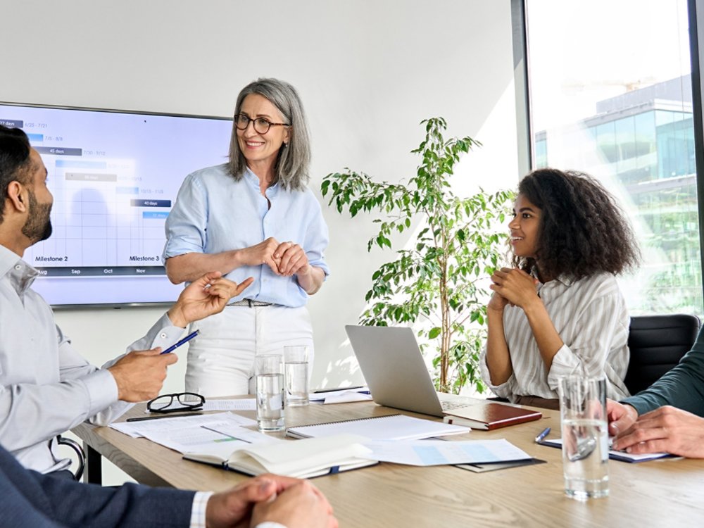 International executive team people having board meeting discussing project results. Diverse employees group working with senior leader brainstorming in office meeting room at presentation training.
