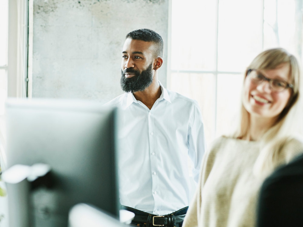 Smiling businessman working with colleagues at office workstation