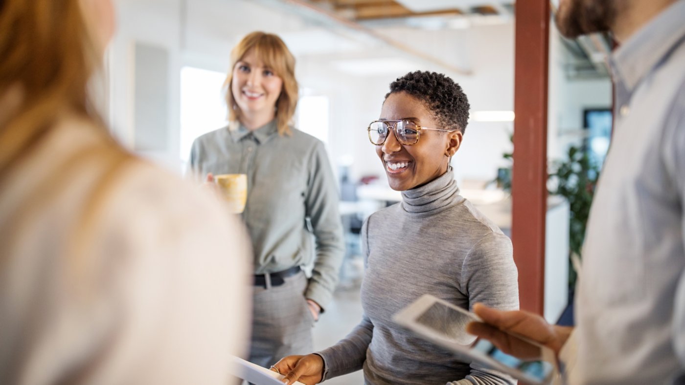 Group of multi-ethnic business team having a standing meeting in office. Business people talking during a break in office.