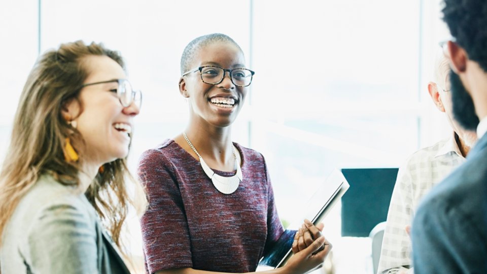 Smiling business colleagues in discussion during informal meeting in start up office