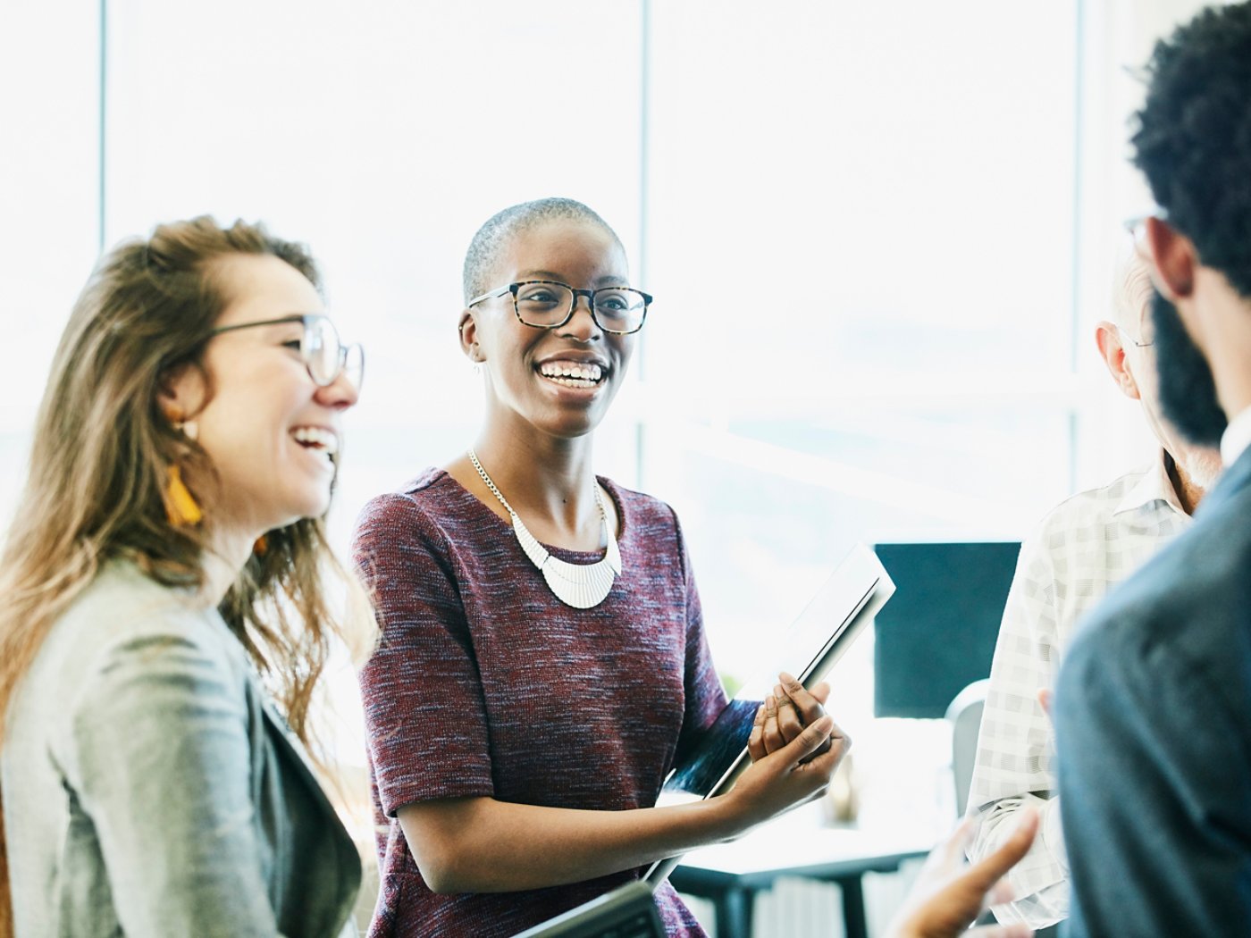 Smiling business colleagues in discussion during informal meeting in start up office