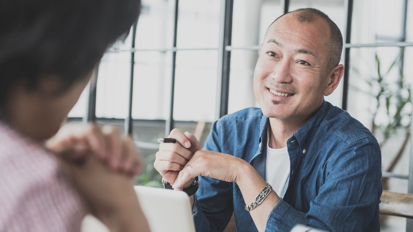 Candid portrait of a asian man in his 40's he is in a work meeting at a creative design consultancy in Tokyo , Japan. Japanese creative in discussion with work colleague.