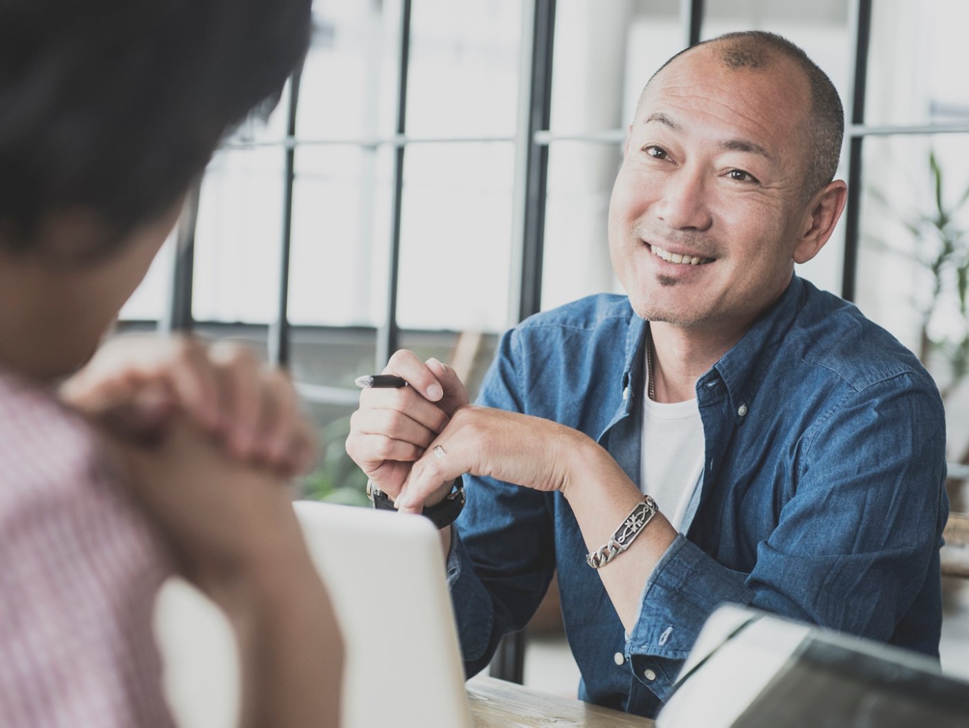 Candid portrait of a asian man in his 40's he is in a work meeting at a creative design consultancy in Tokyo , Japan. Japanese creative in discussion with work colleague.