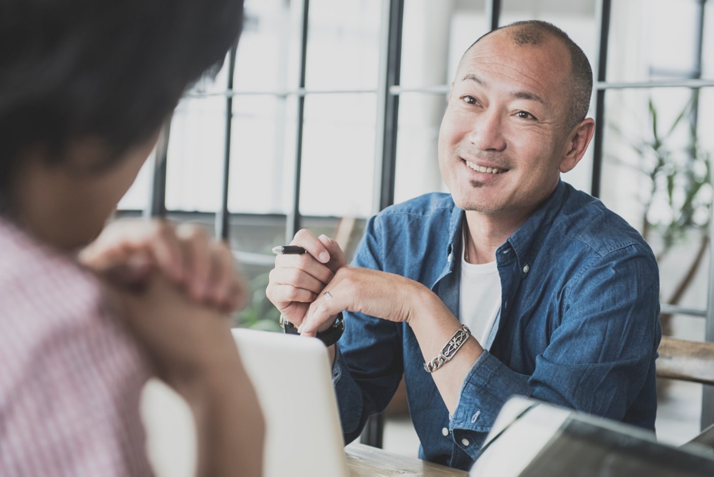 Candid portrait of a asian man in his 40's he is in a work meeting at a creative design consultancy in Tokyo , Japan. Japanese creative in discussion with work colleague.