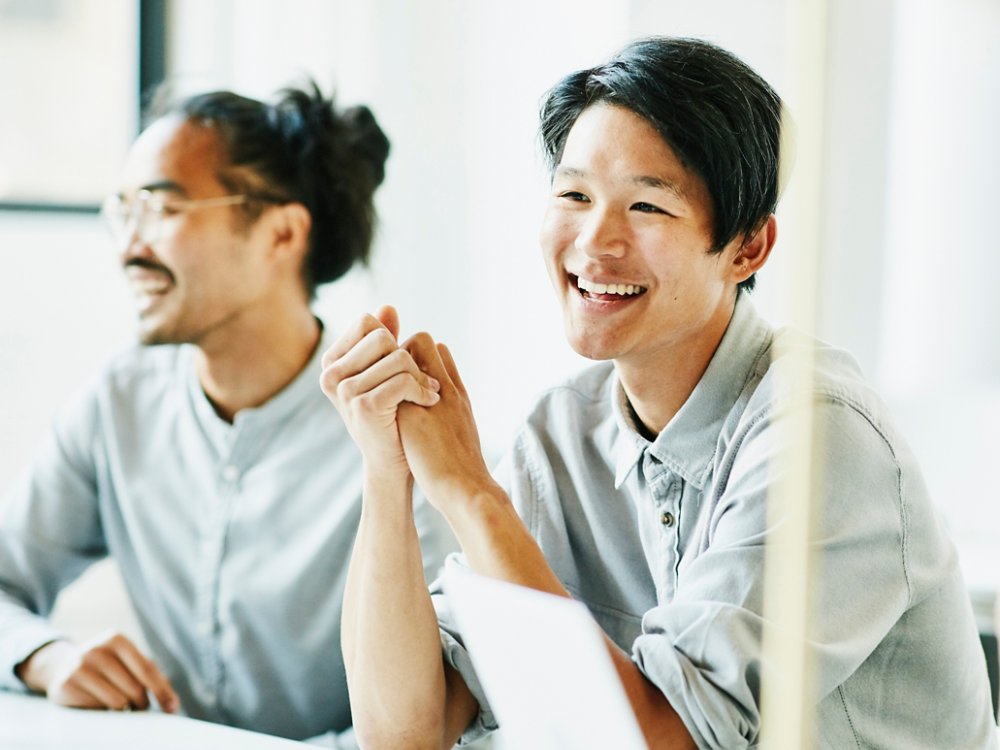 Laughing businessman in discussion with colleagues during meeting in office conference room