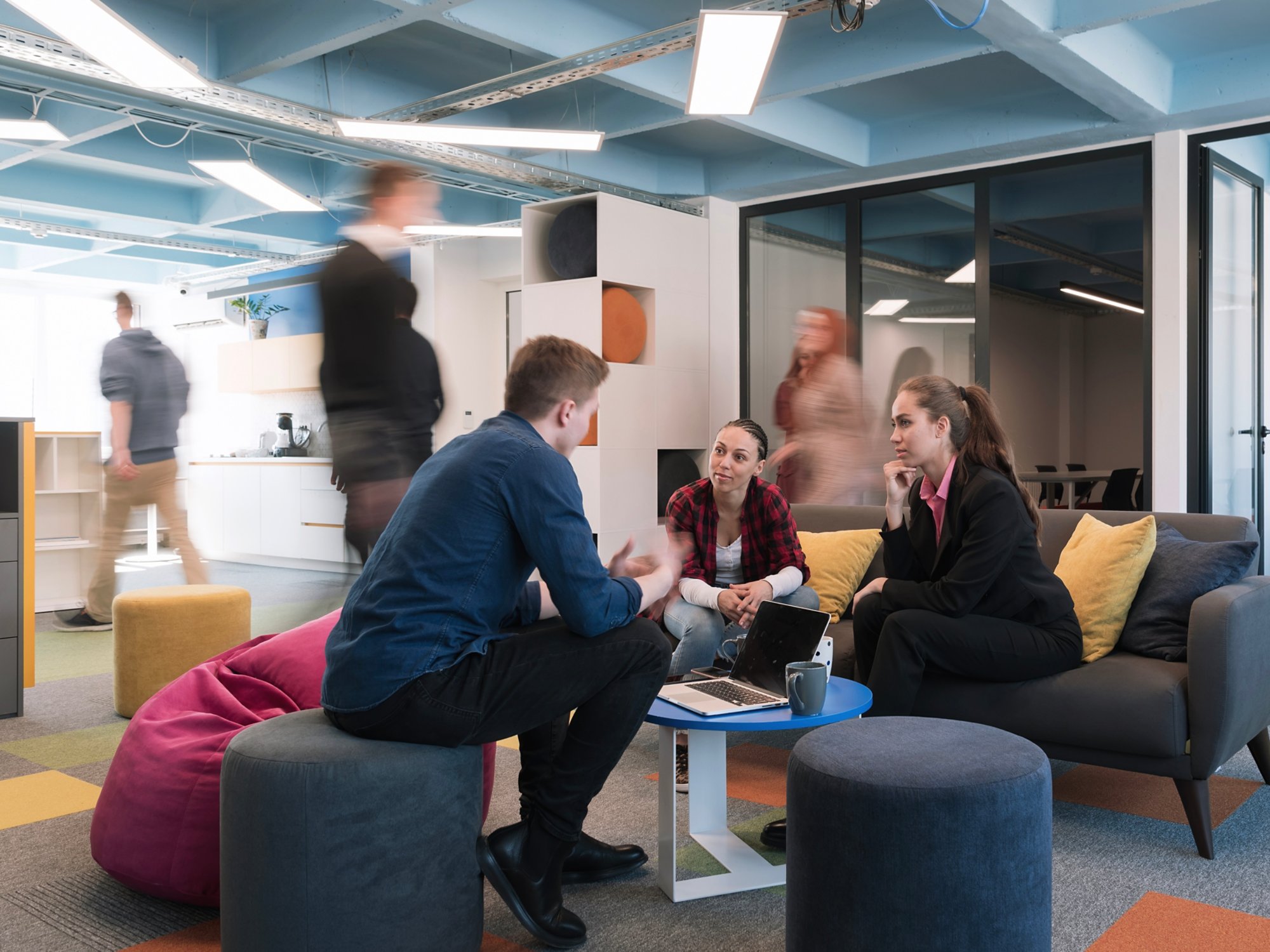 Multiethnic startup business team on meeting in a modern bright open space coworking office. Brainstorming, working on laptop. Group of coworkers walking around in motion blur. High quality photo