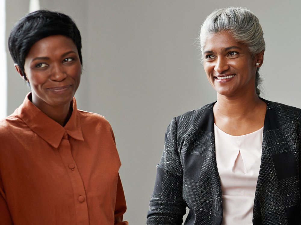 Smiling businesswoman with female colleagues looking away at workplace