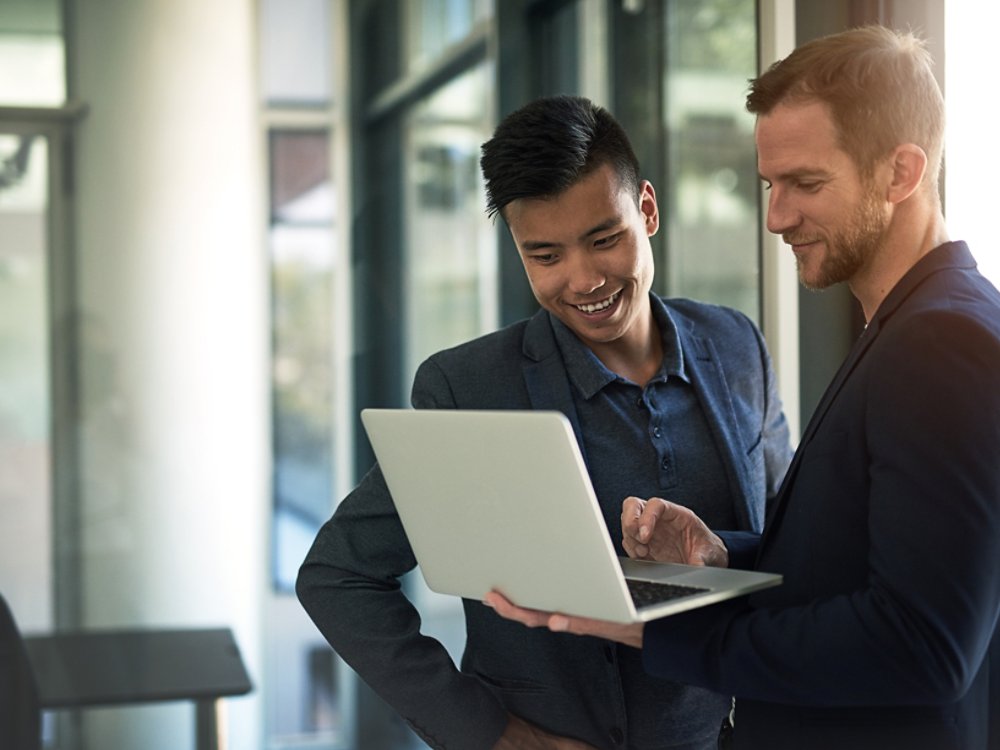 Shot of two businessmen discussing something on a laptop in an office