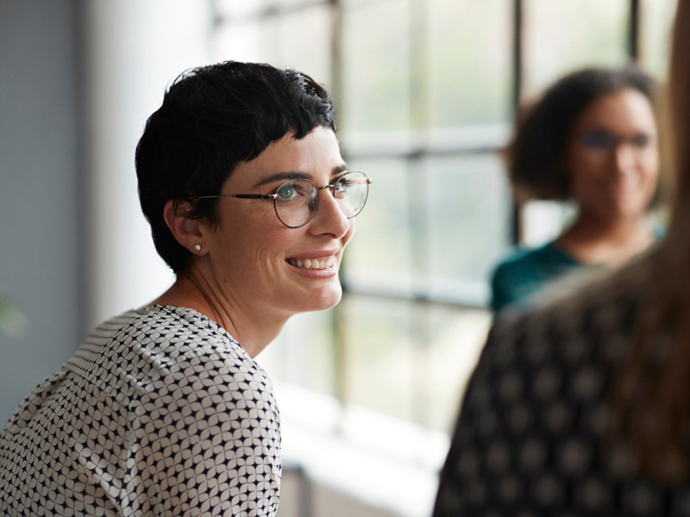 Smiling entrepreneur looking at female colleague while sitting at workplace 4X3