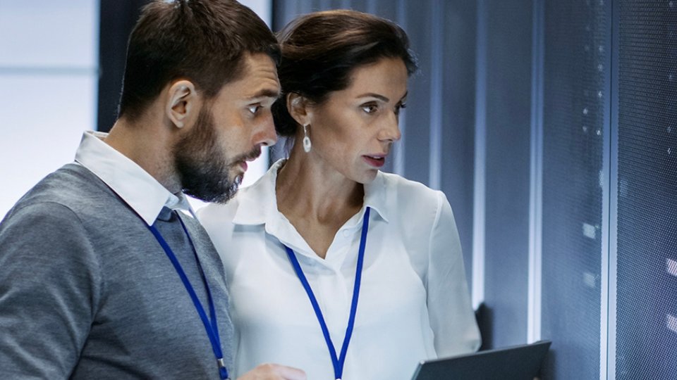 Man and woman technicians working in server room with laptop
