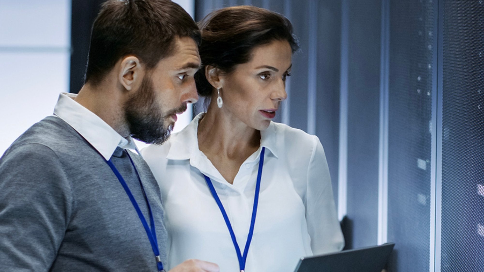 Man and woman technicians working in server room with laptop