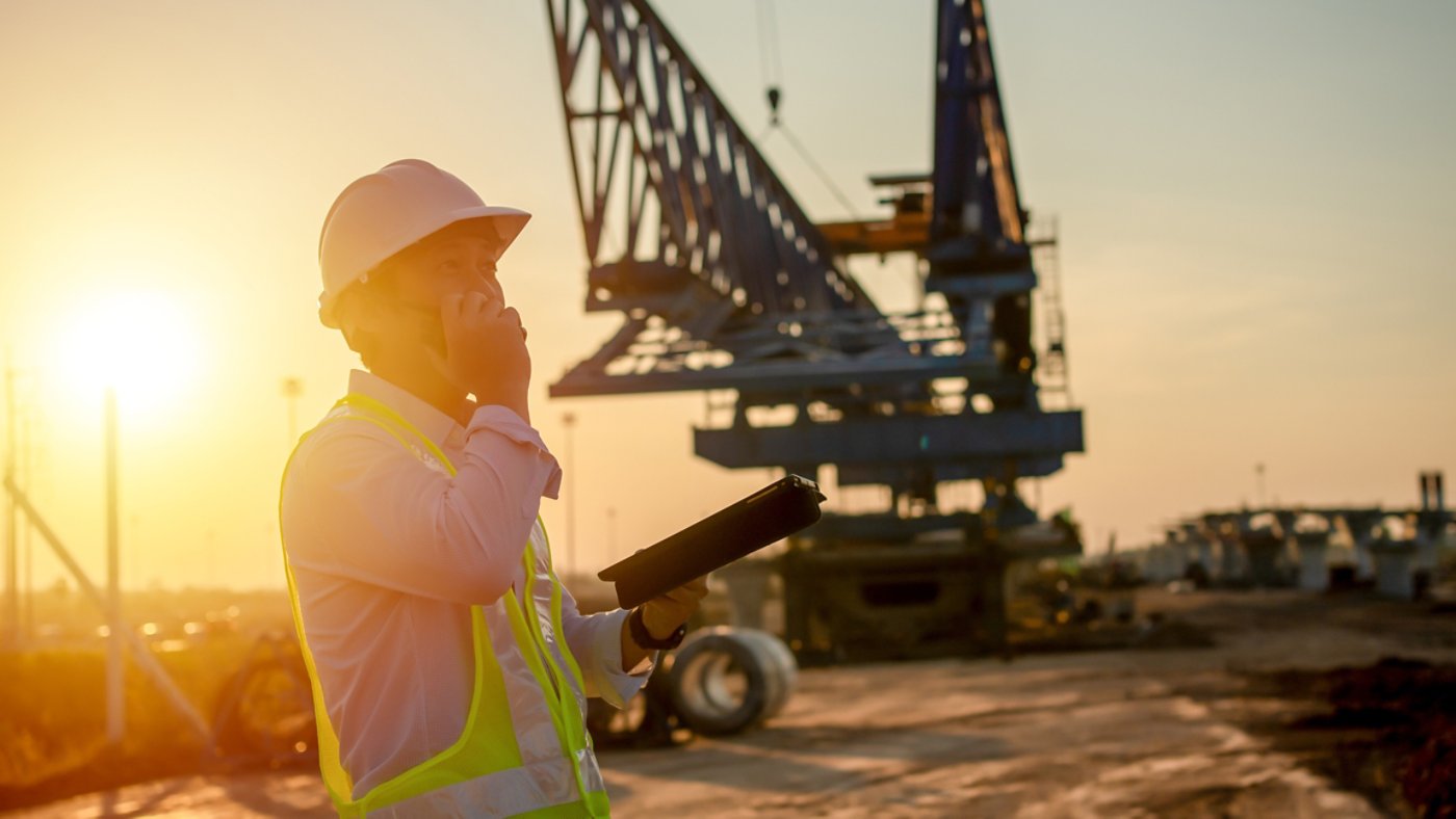 Engineer talking on walkie-talkie and using smart phone for working at construction site