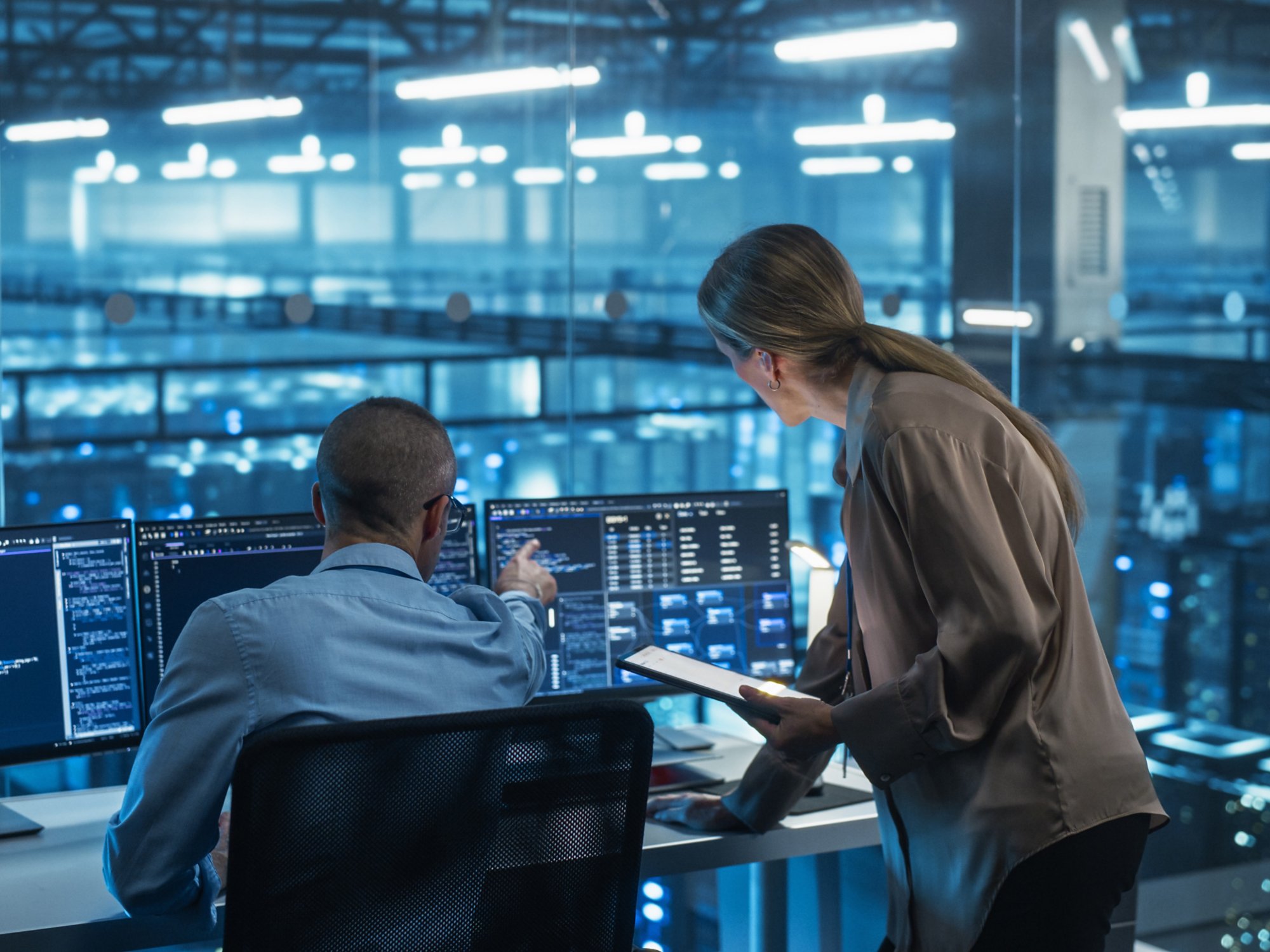 Male Engineer and Female Team Leader Collaborate on a Project in a Modern Data Center Office. Specialists Analyzing Complex Systems on Multiple Screens to Improve Software Performance