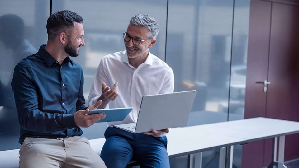 Business manager and colleague discussing project in modern office
