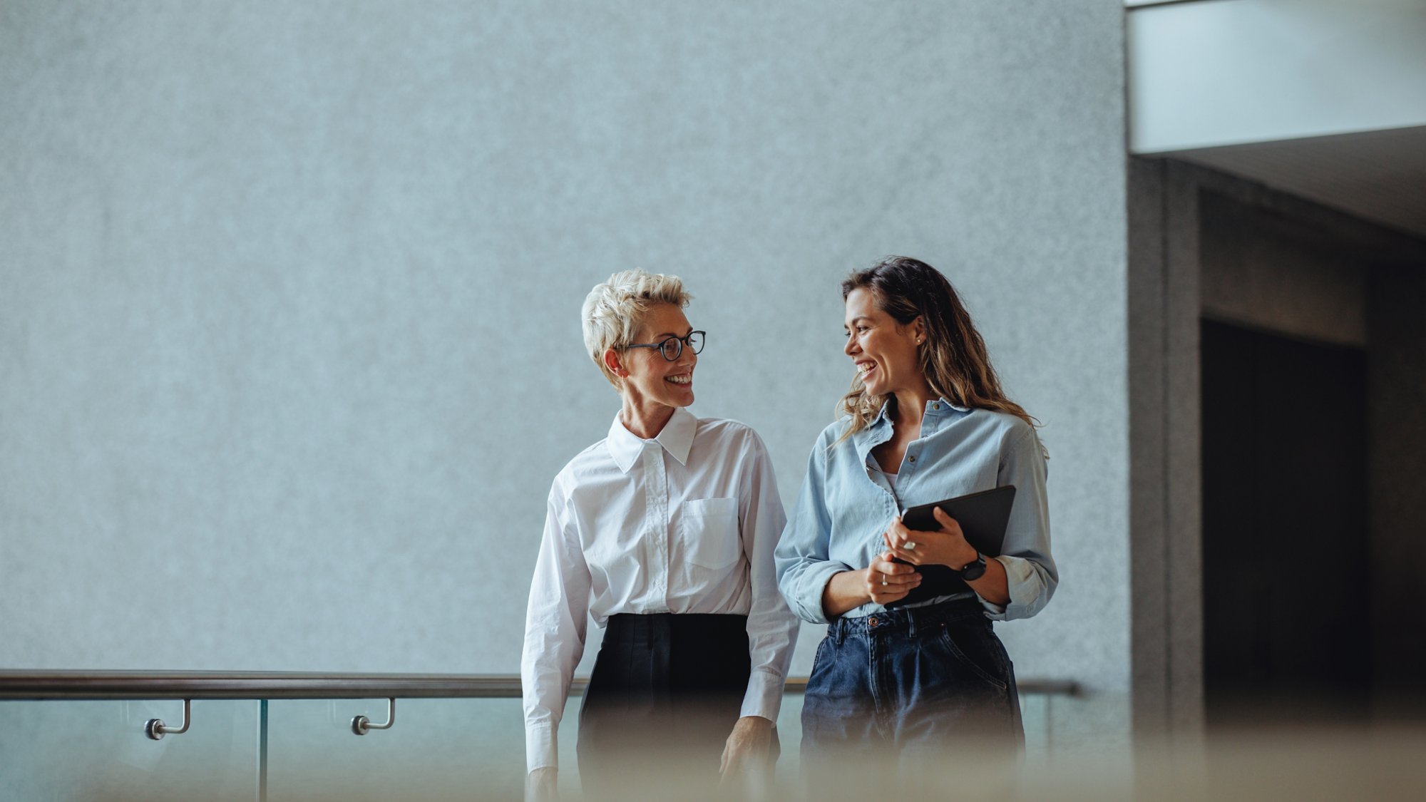 Two business women smiling as they have a discussion in a professional office. Mature woman getting a briefing on the company's performance from her administrative assistant.