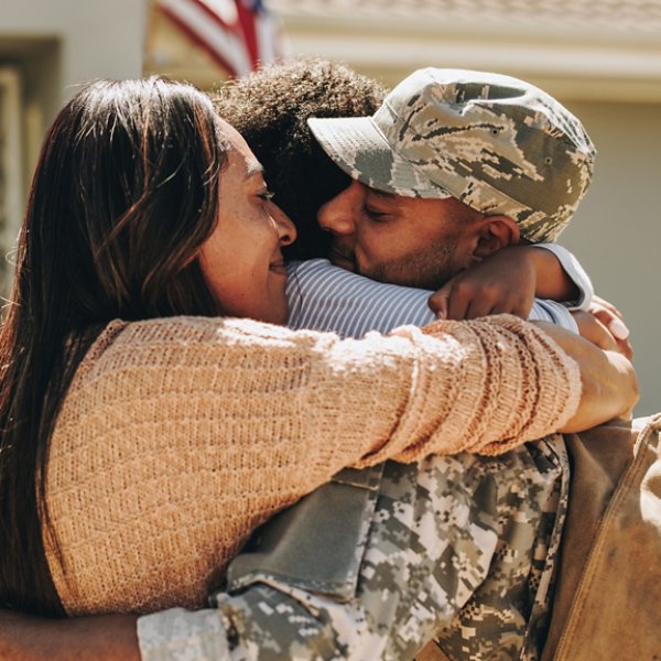 Military serviceman reuniting with his family after deployment. Soldier embracing his wife and daughter after returning from the army. Military man receiving a warm welcome from his family at home.