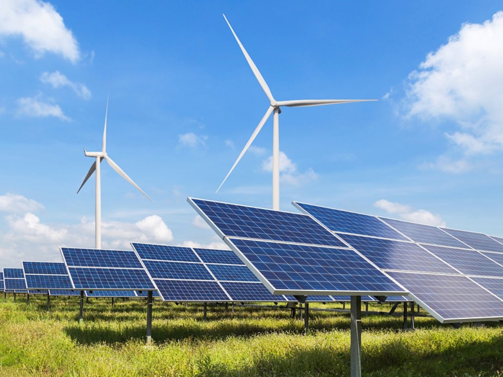 windmills and solar panels in a field under blue skies