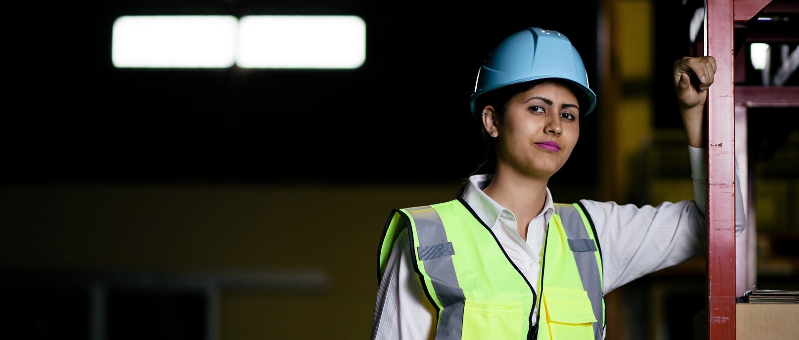 female warehouse worker with helmet and safety vest
