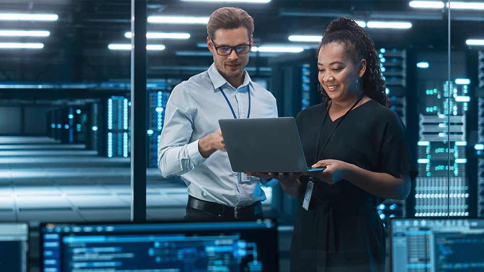 man and woman IT technicians in server room looking at laptop 2