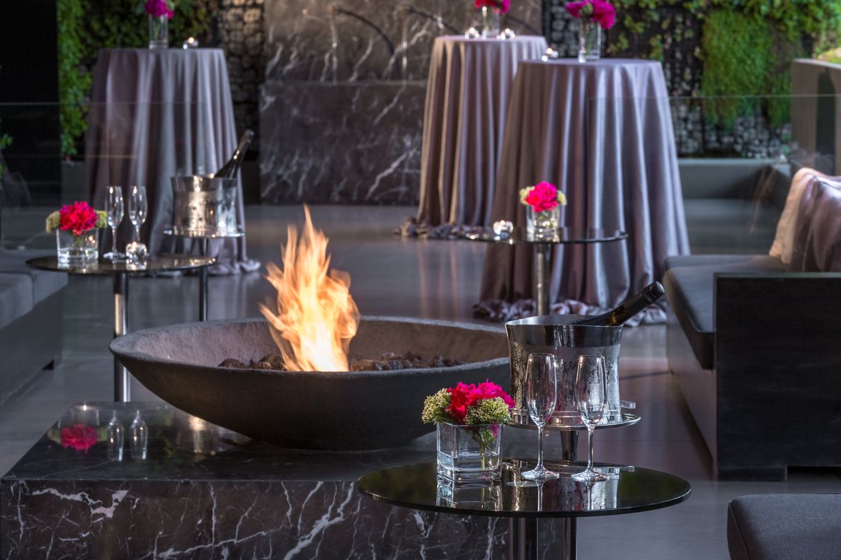 Close up detail of firepit, marble table, and cocktail tables with linens and floral arrangements. 