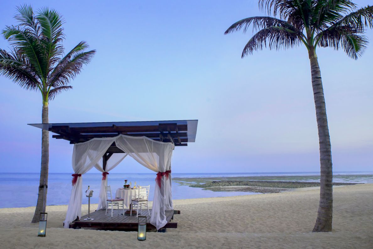 Gazebo on the beach decorated for a romantic dinner at dusk.