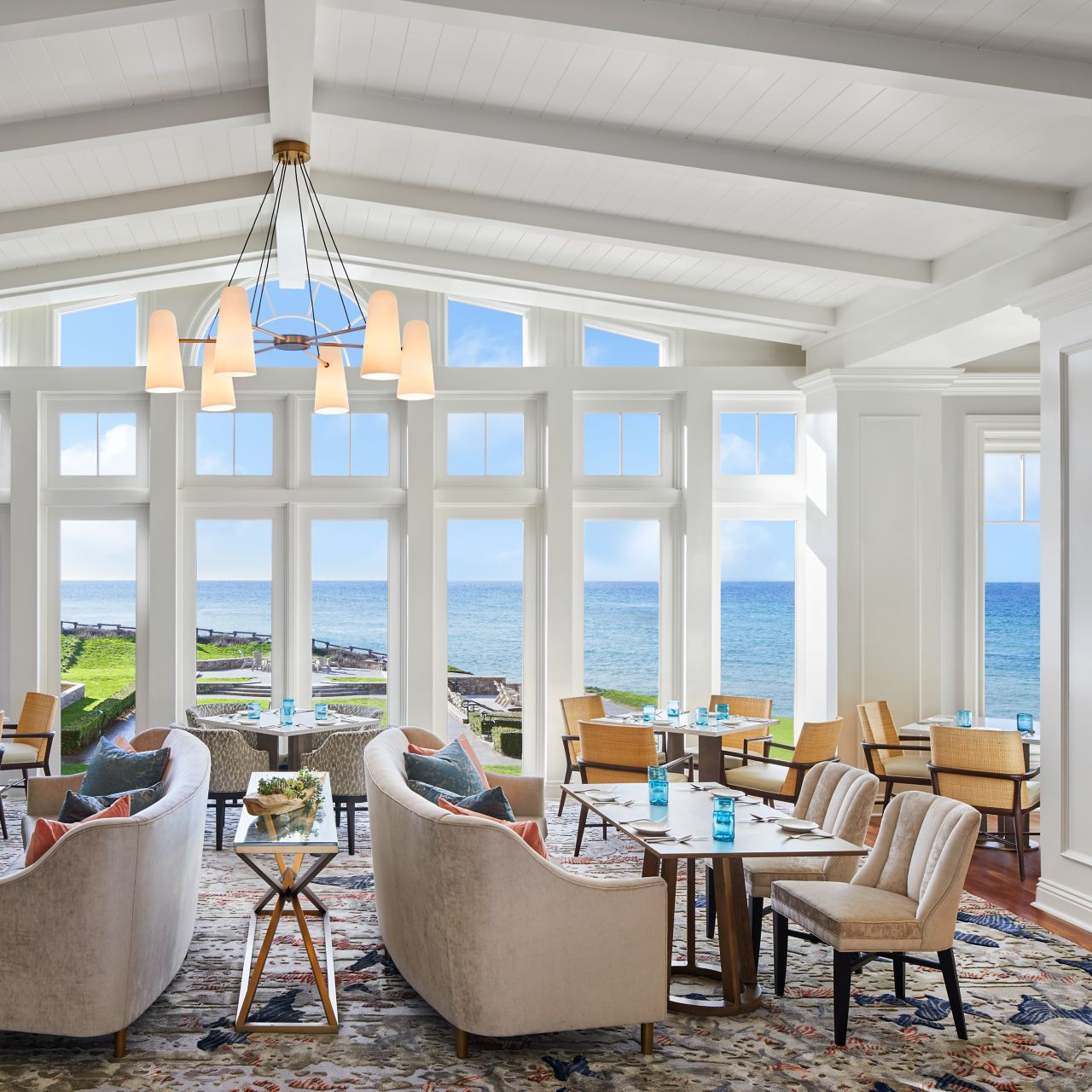 Airy space with dining tables and an entire wall of windows overlooking the ocean
