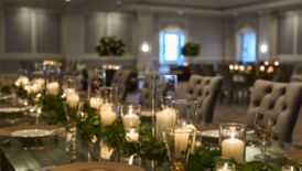 A long dining table with formal centerpieces and settings