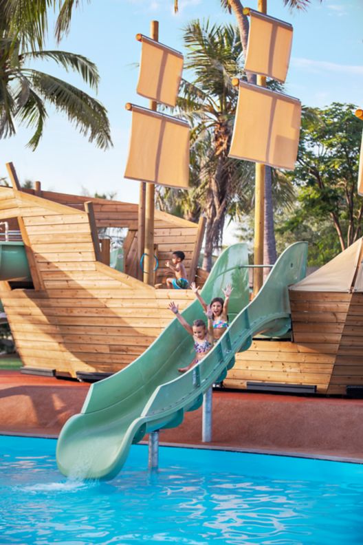 Two children on a slide at a water park about to plunge into a pool.