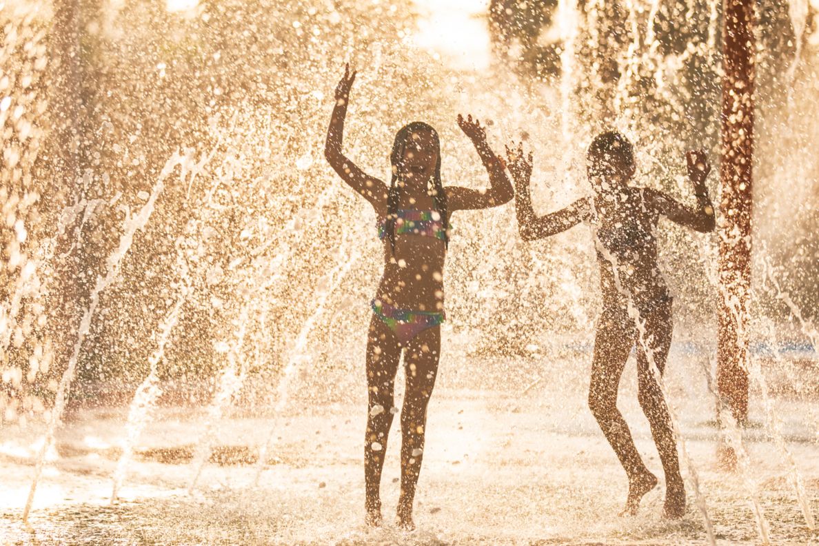 Two young girls playing in a fountain.
