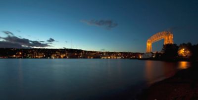 River with very tall bridge in the background lit up at night