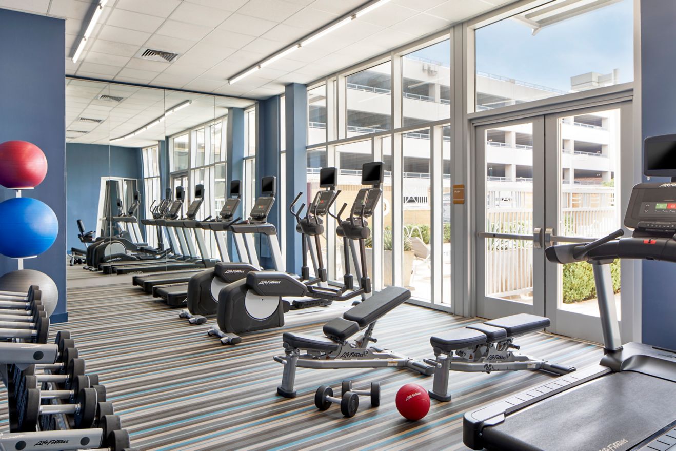 Well-lit fitness center with ellipticals and tread