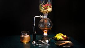 A multi-level glass infuser with fruit being made into a drink
