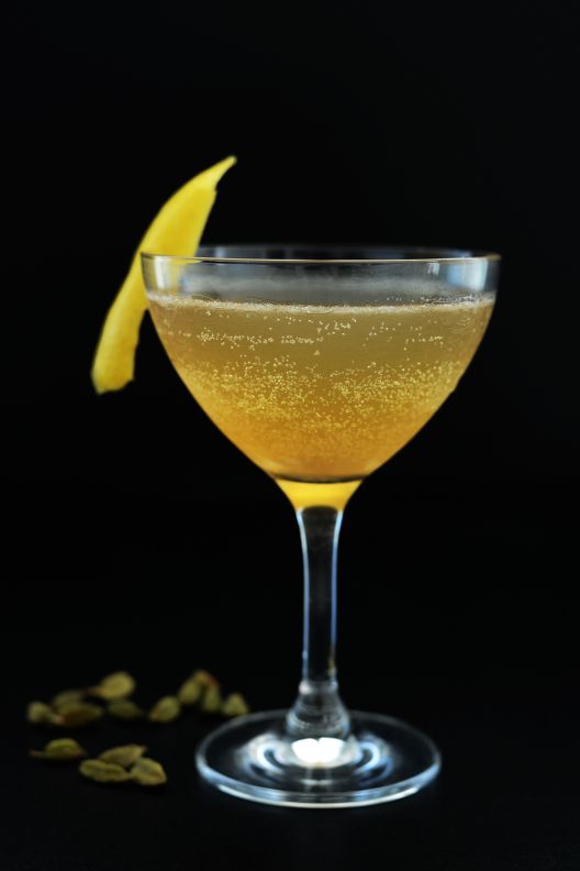 A cocktail in a martini glass with a lemon wedge.